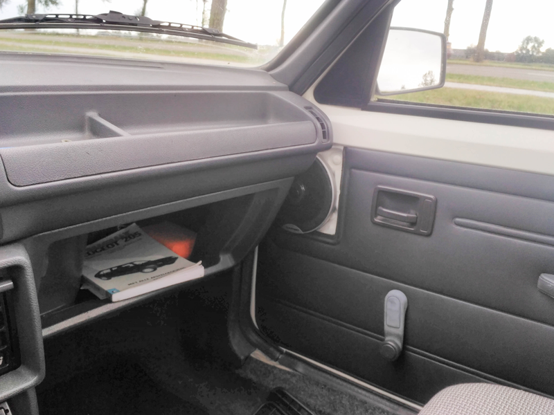Base model car. Glove box lid was optional. As were the door bins. I don’t believe it originally came without speaker covers though.